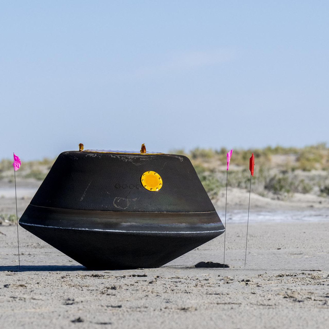 The sample return capsule on the ground in the desert